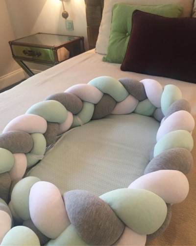 Almofada trançada de bebé colorida sobre colchão e almofadas