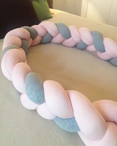 Trança decorativa em tecido rosa claro e cinza sobre superfície bege