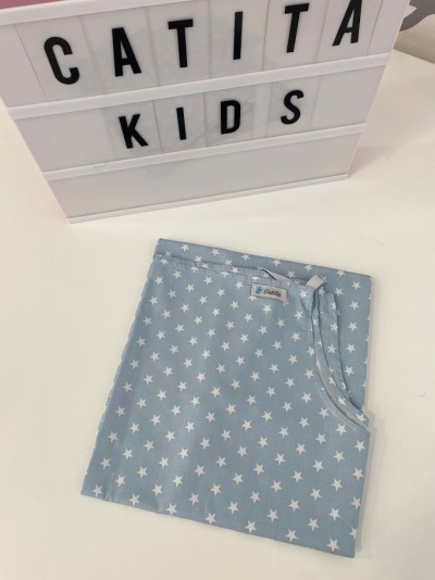 Tecido azul claro com estrelas brancas e etiqueta Catita sobre superfície branca com caixa de luz CATITA KIDS.