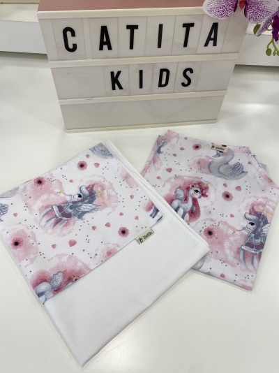 Tecidos infantis com estampas de unicórnios e cisnes em cores rosa, branco e cinza, próximo a letreiro com 'CATITA KIDS'.
