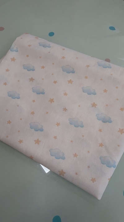 tecido branco com nuvens azuis e estrelas cor de bege dobrado