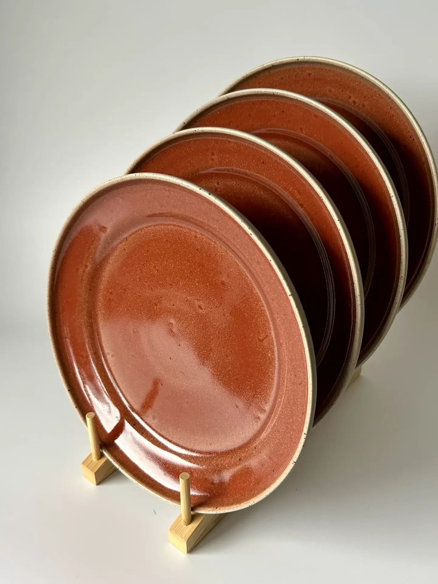 Conjunto de quatro pratos redondos castanho-avermelhados em suporte de madeira