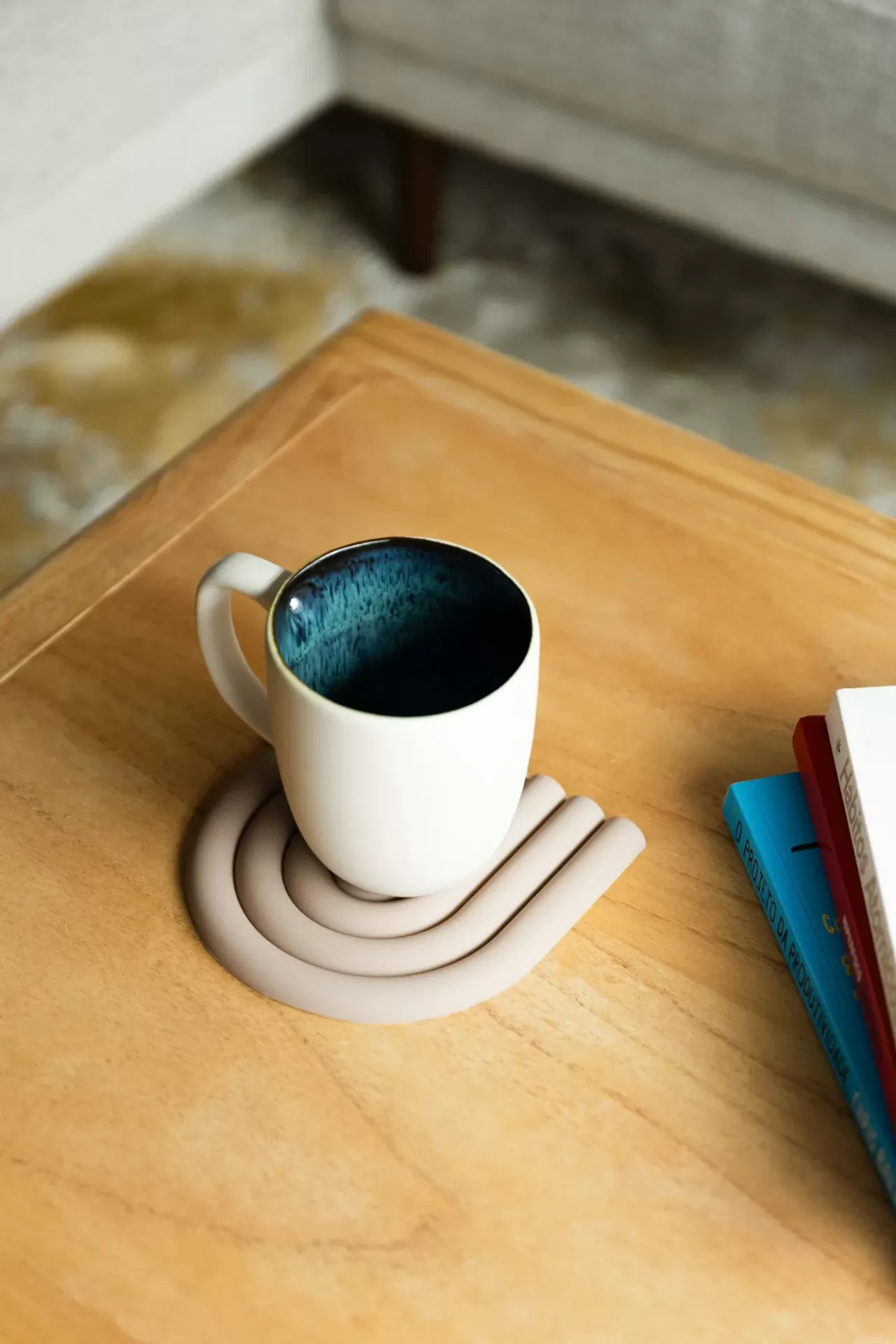 Caneca branca com interior azul em base bege numa mesa de madeira clara