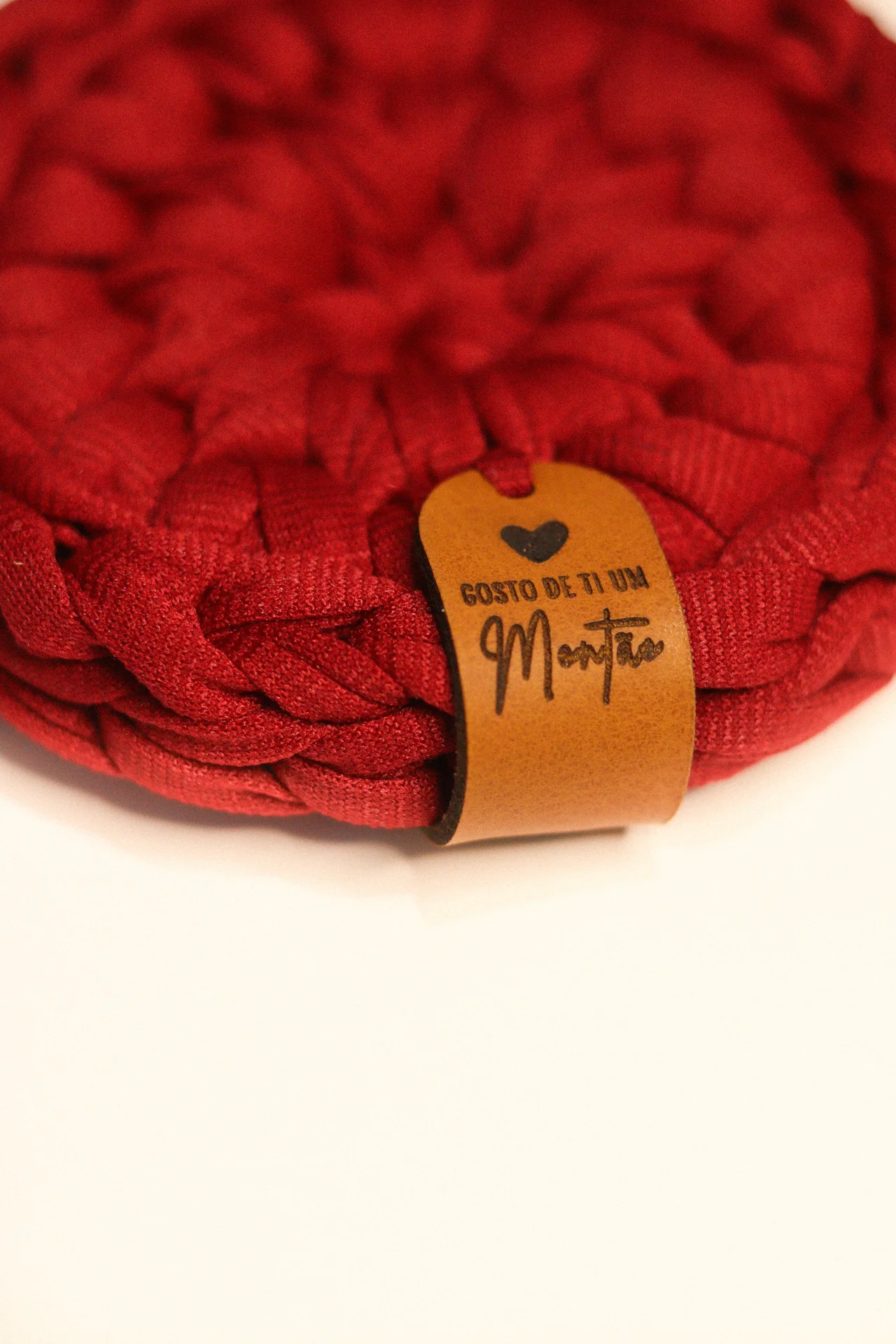 Produto artesanal vermelho com etiqueta de couro com texto em português