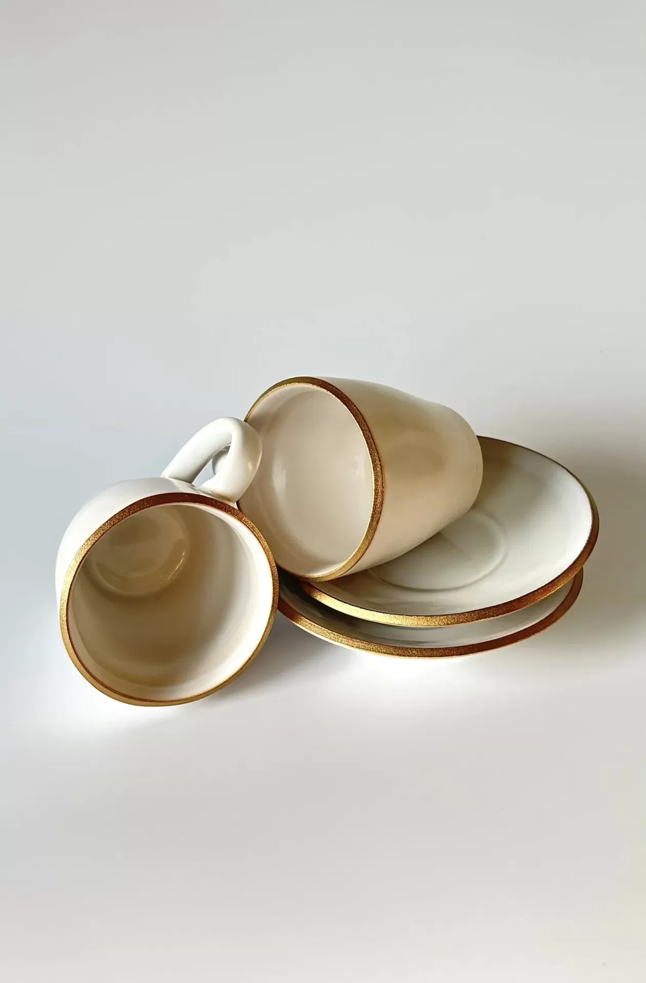 Conjunto de chávenas e pires brancos com bordas douradas em fundo branco.