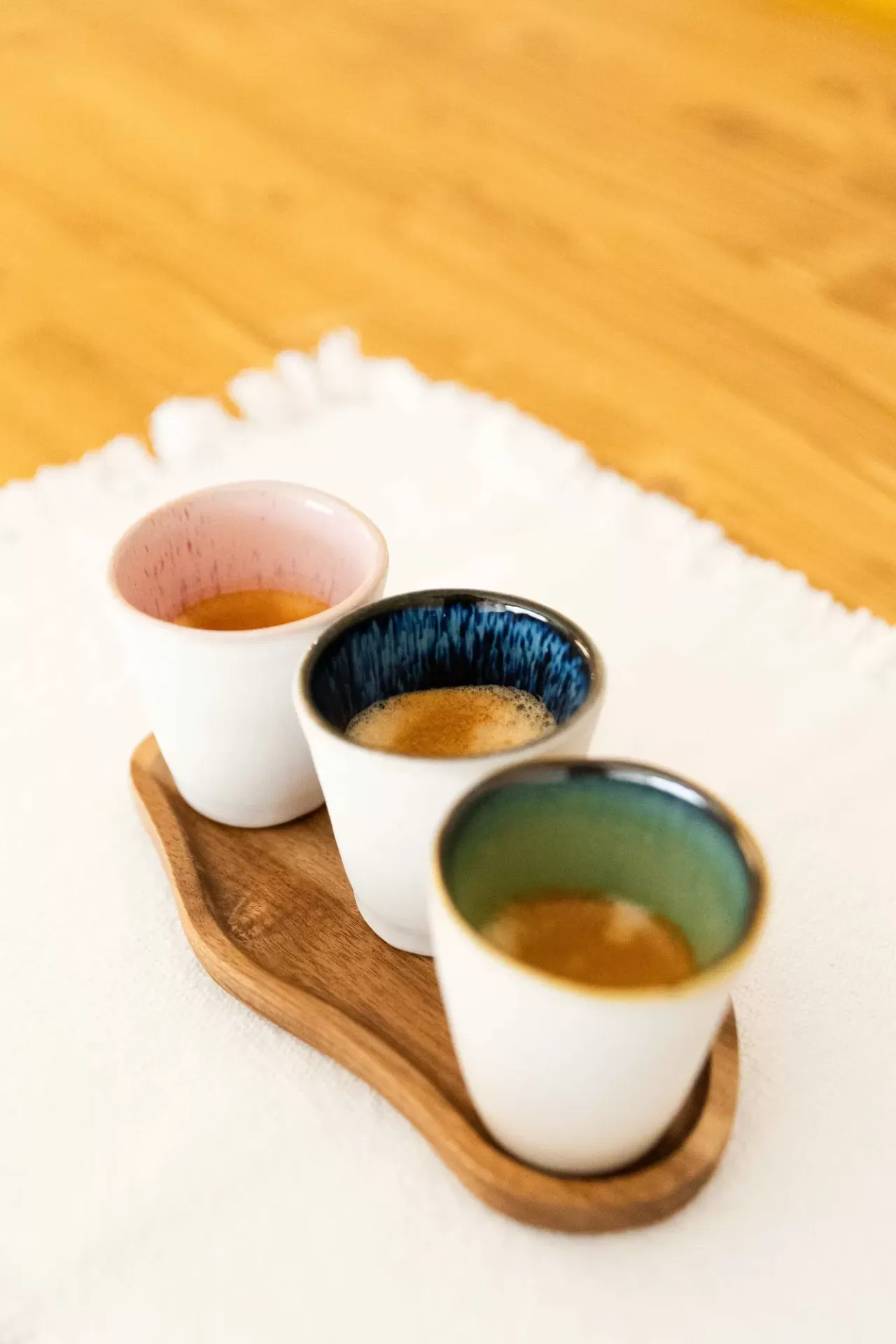 Três chávenas de cerâmica coloridas sobre tabuleiro de madeira