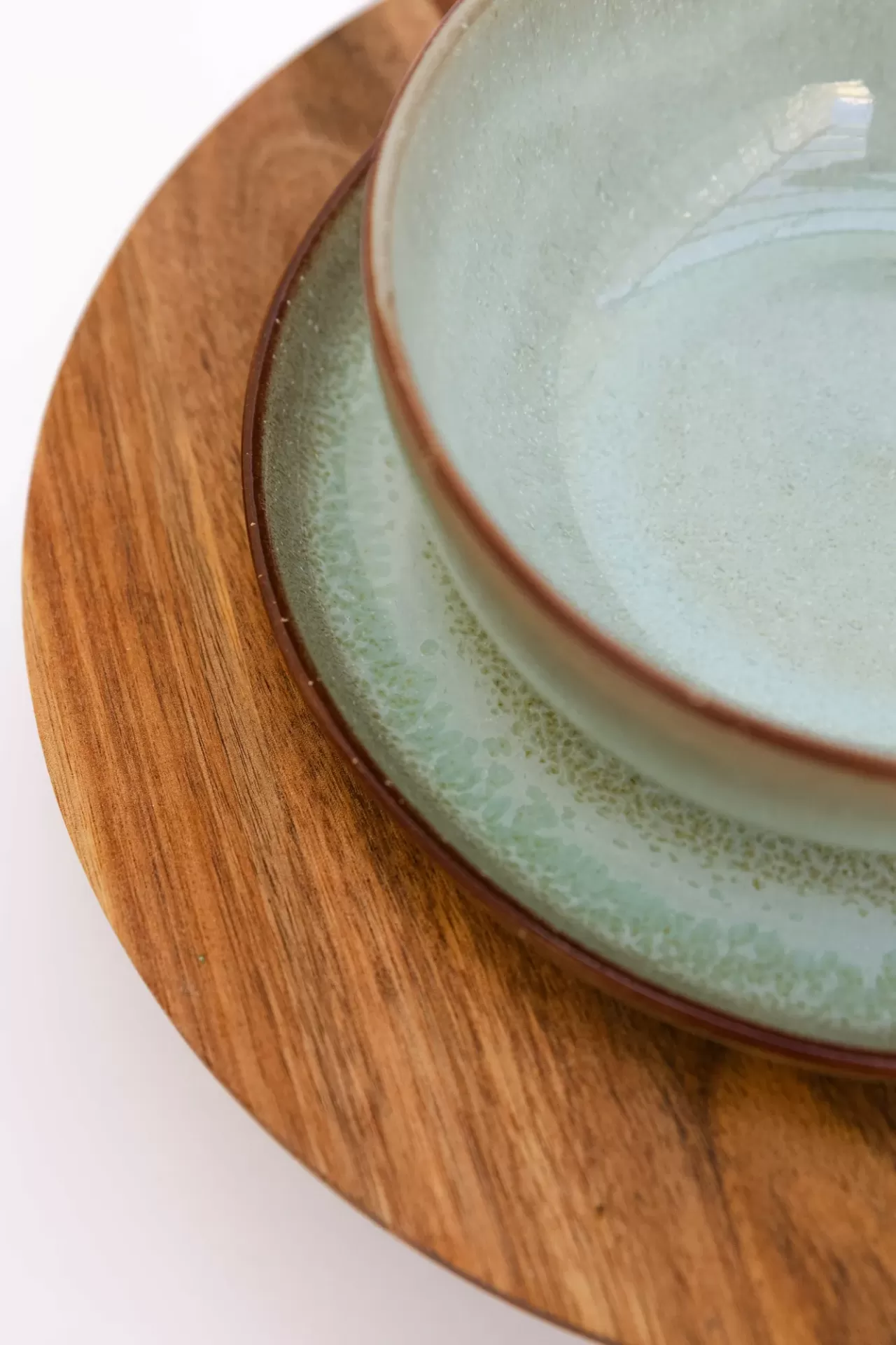 Taça e prato de cerâmica azul claro sobre base de madeira