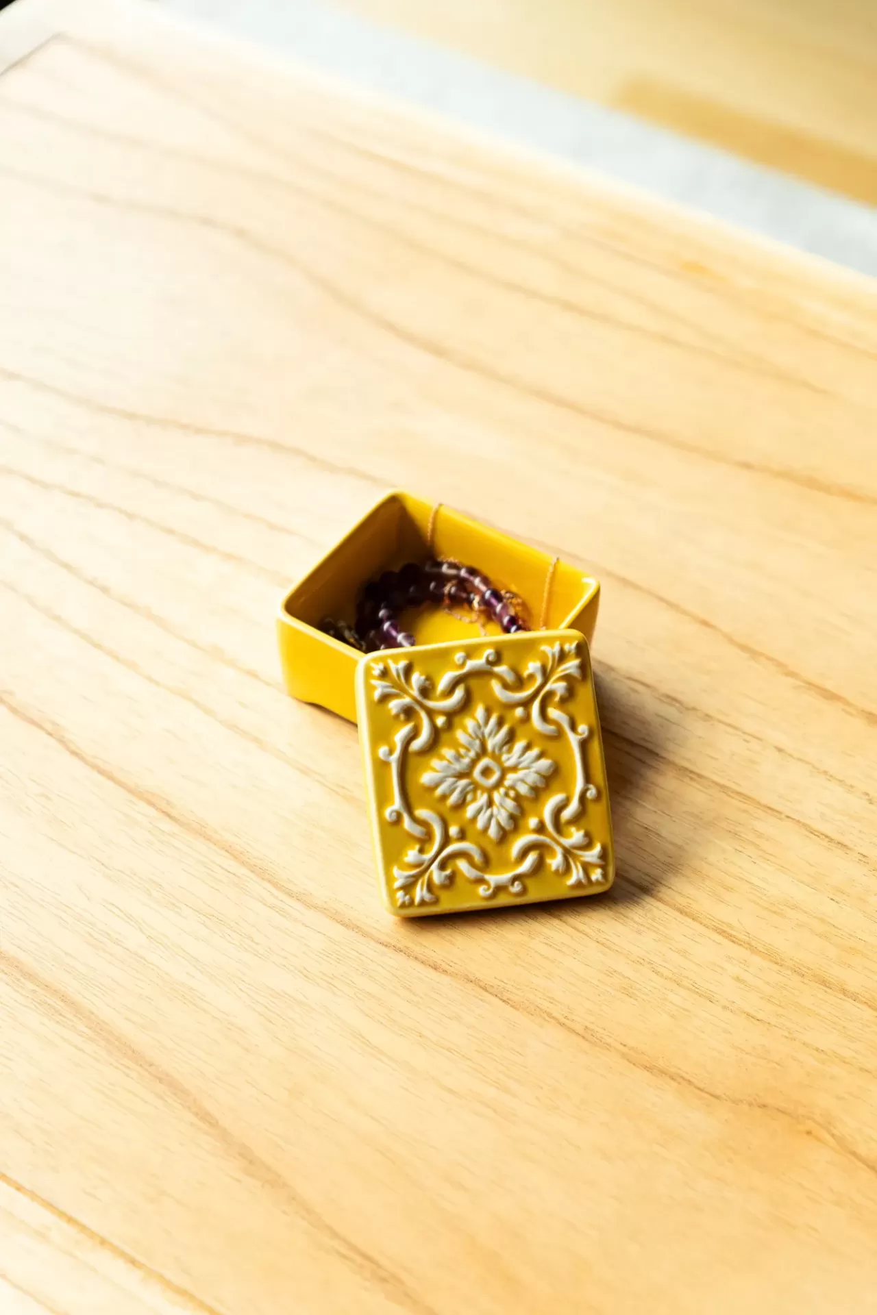 caixa decorativa amarela em cerâmica com pulseira roxa no interior