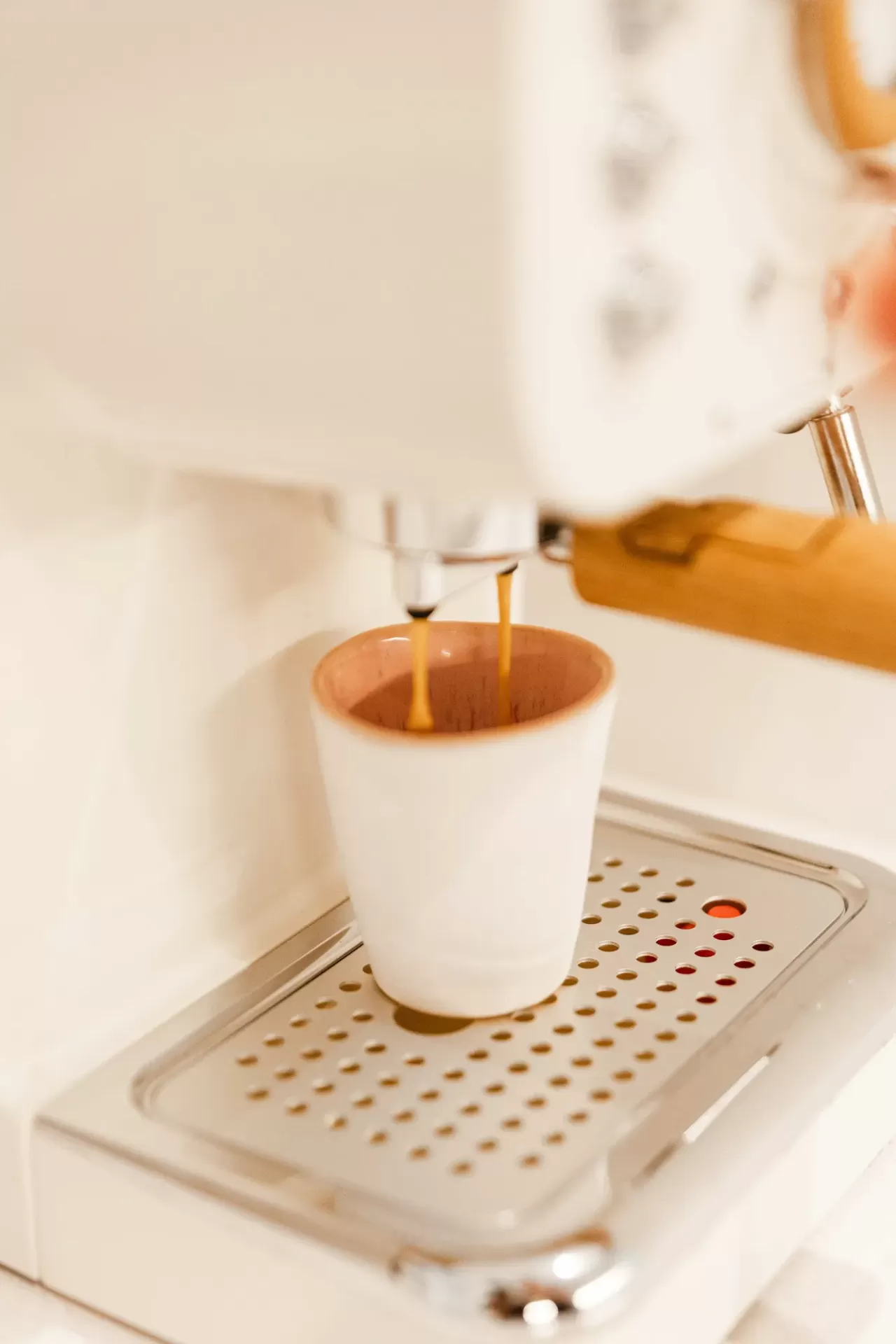 Máquina de café branca a preparar café para uma chávena branca com interior castanho