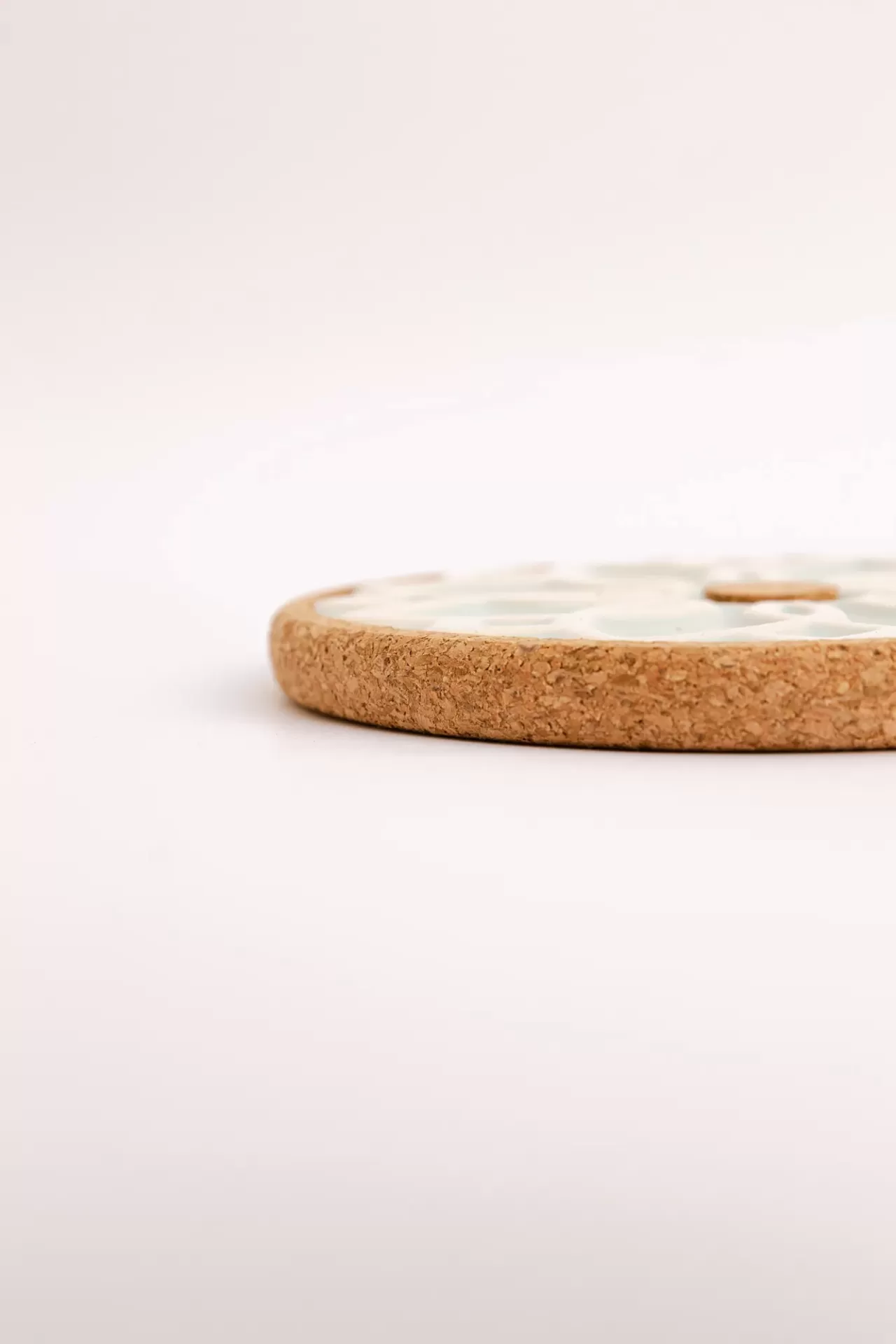 Base redonda de cortiça com topo branco e bolinhas douradas