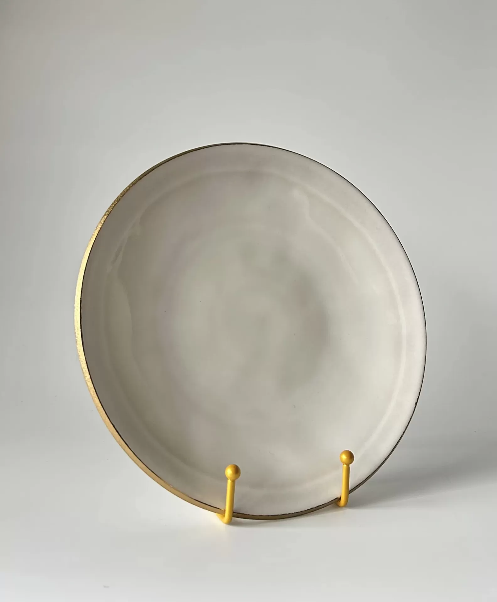 Prato branco com bordo dourado em suporte amarelo