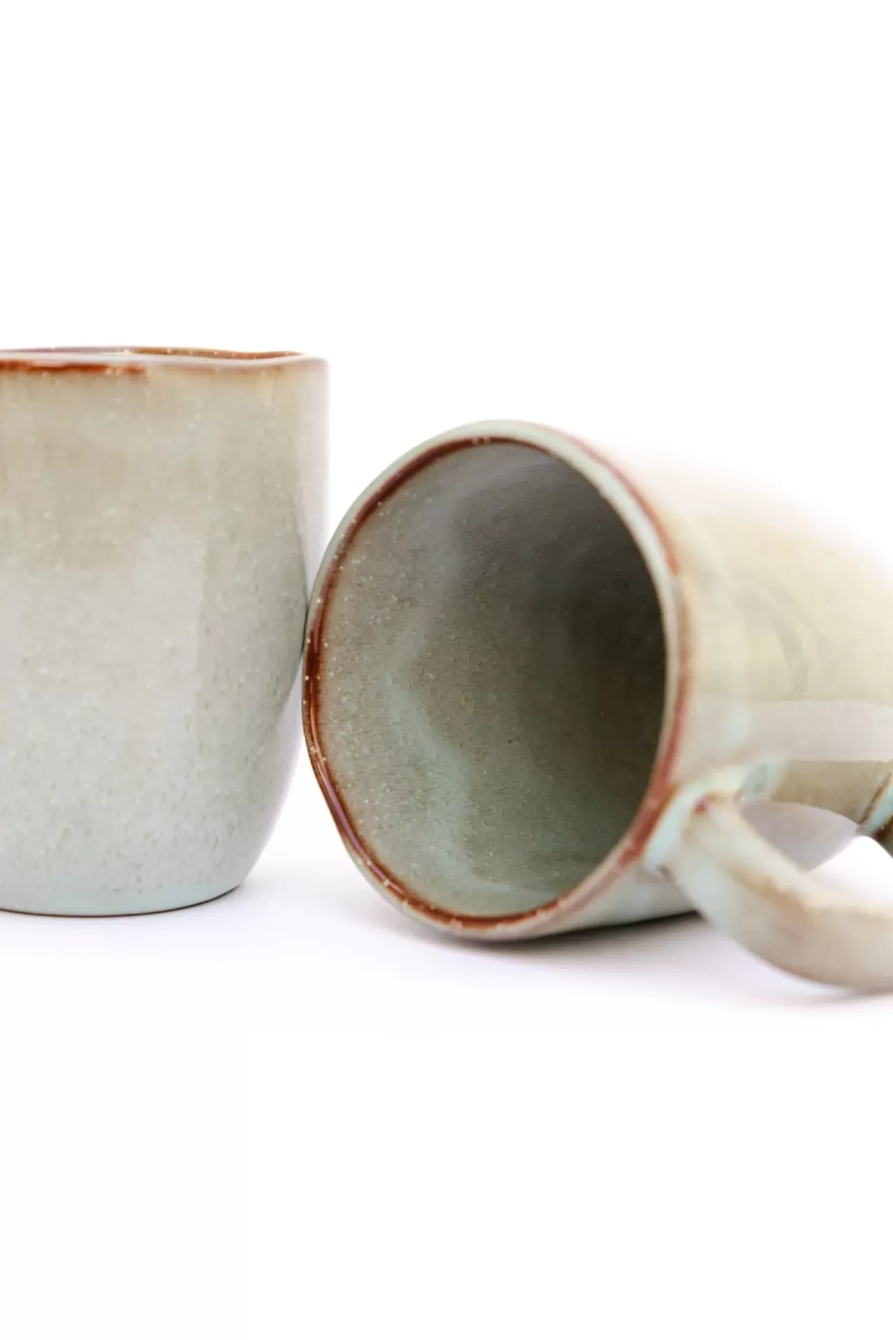 Dois canecos de cerâmica cinza claro com bordas castanhas sobre fundo branco.