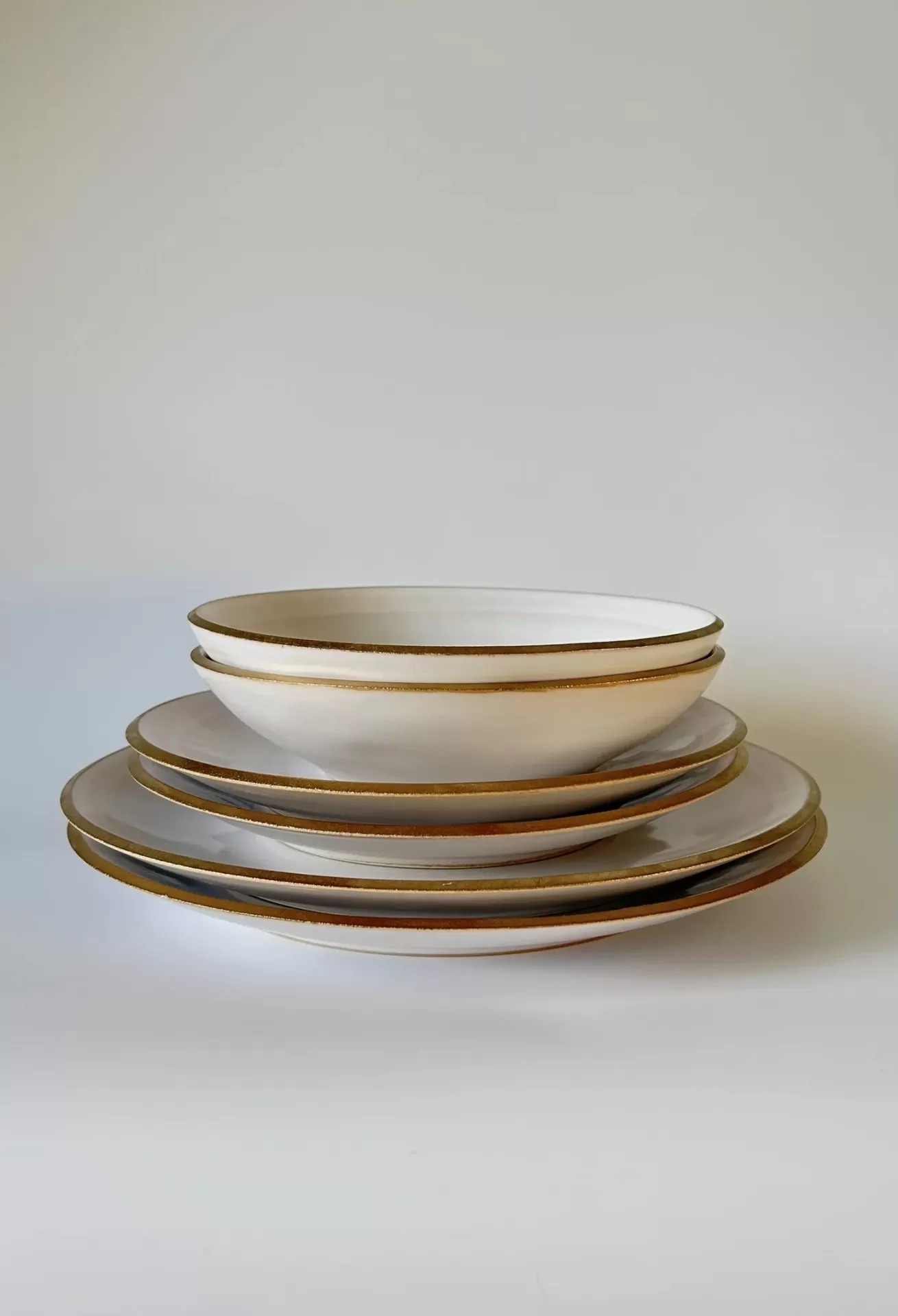 Conjunto de pratos brancos com bordas douradas empilhados