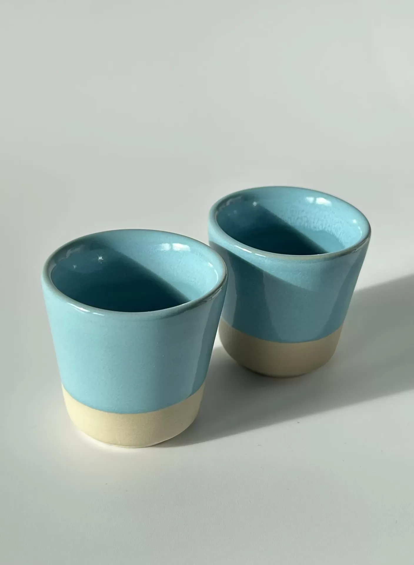 Dois copos pequenos em cerâmica azul claro e bege
