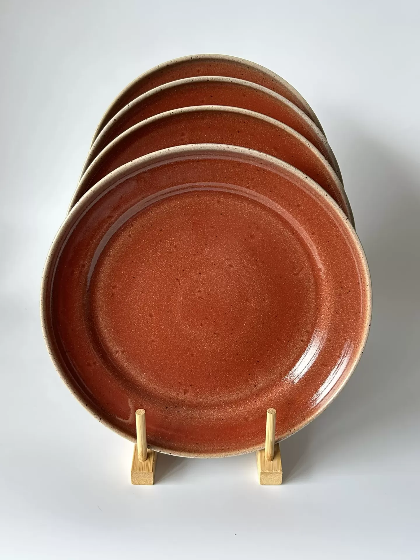 Conjunto de quatro pratos de cerâmica terracota em suporte de madeira.