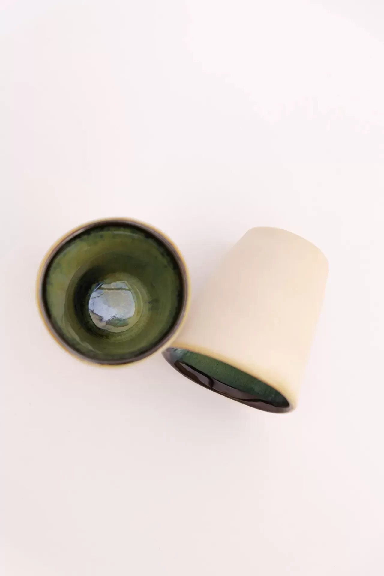 Copos de cerâmica com interior verde escuro e exterior branco sobre fundo branco