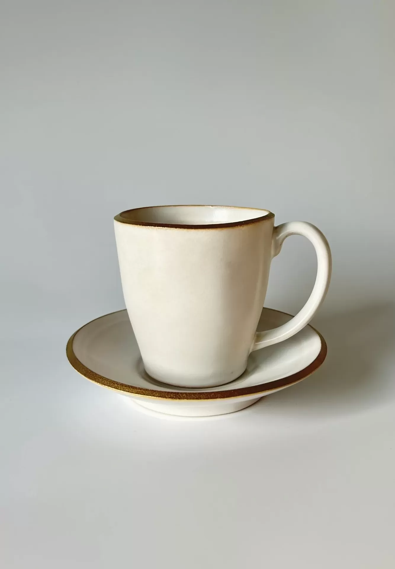 chávena creme com bordas douradas sobre pires
