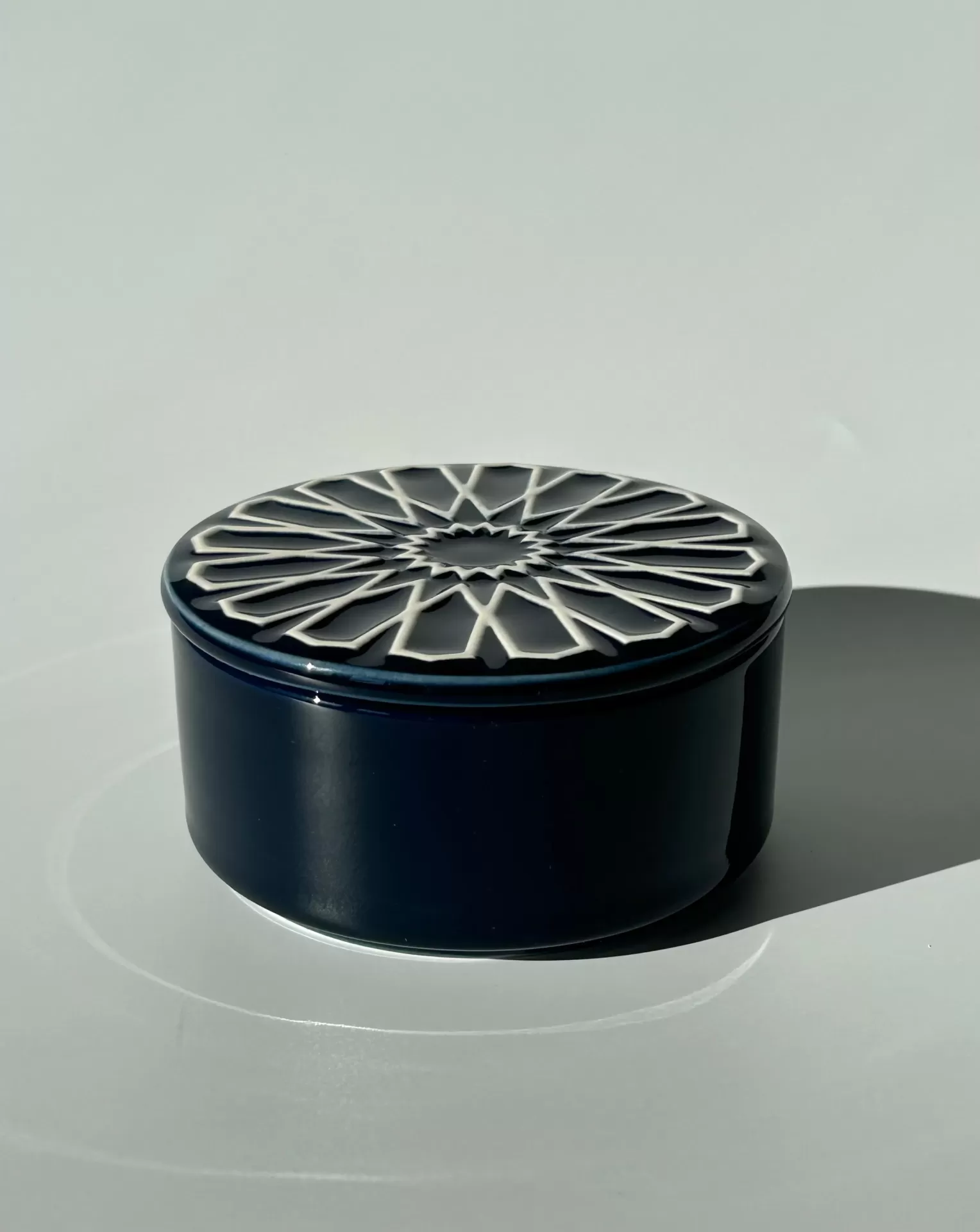 Caixa cerâmica azul escura com tampa decorada e padrão geométrico branco