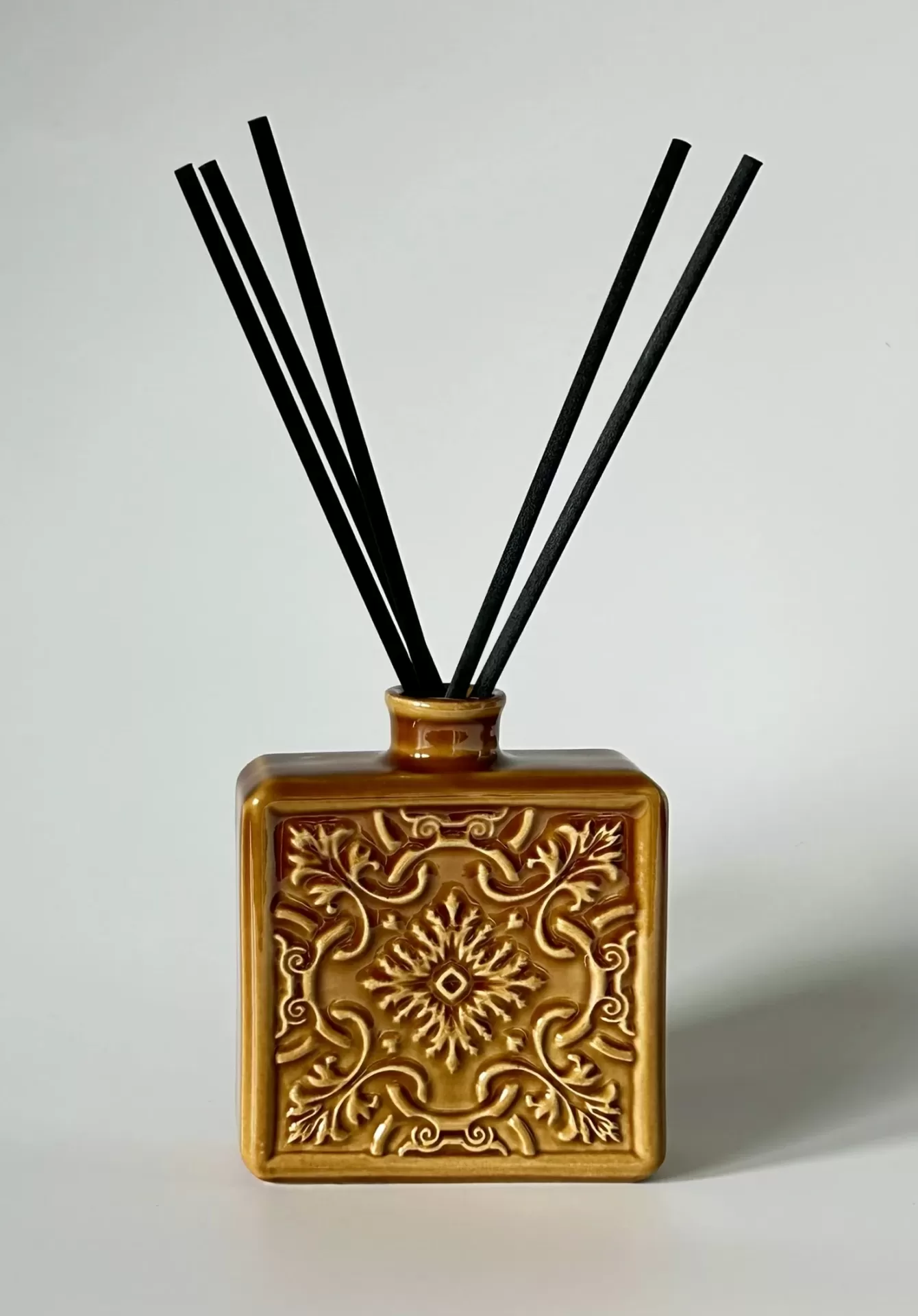 Frasco quadrado cerâmico castanho com relevo floral e varetas pretas para difusor de ambiente