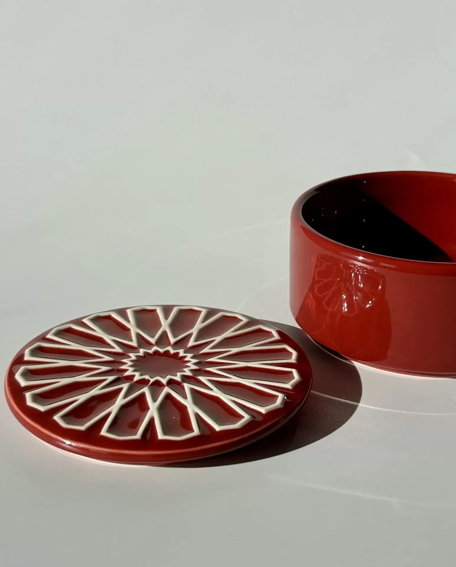 Caixa redonda de cerâmica vermelha com tampa decorativa e interior preto