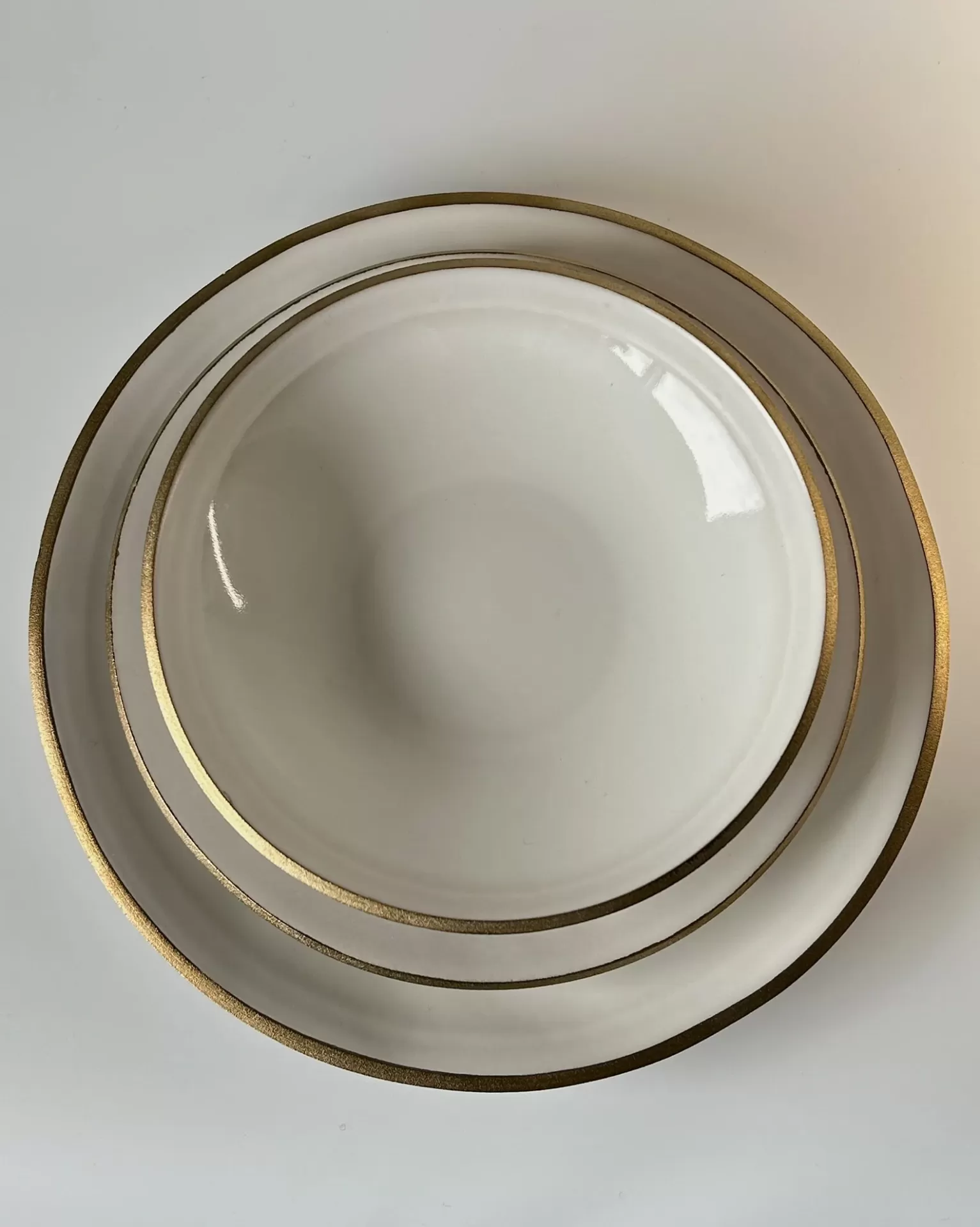 Conjunto de pratos brancos com bordas douradas empilhados visto de cima