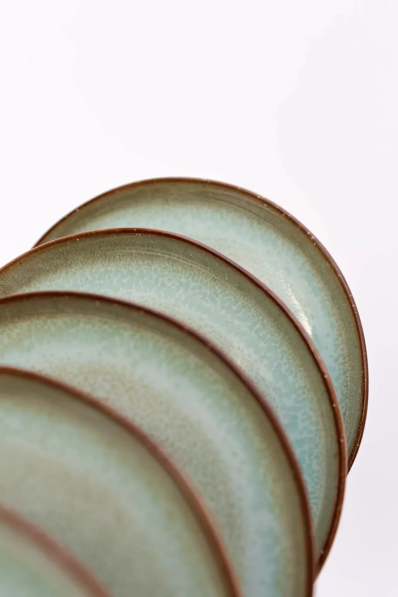 Conjunto de pratos verdes com bordas marrons empilhados.