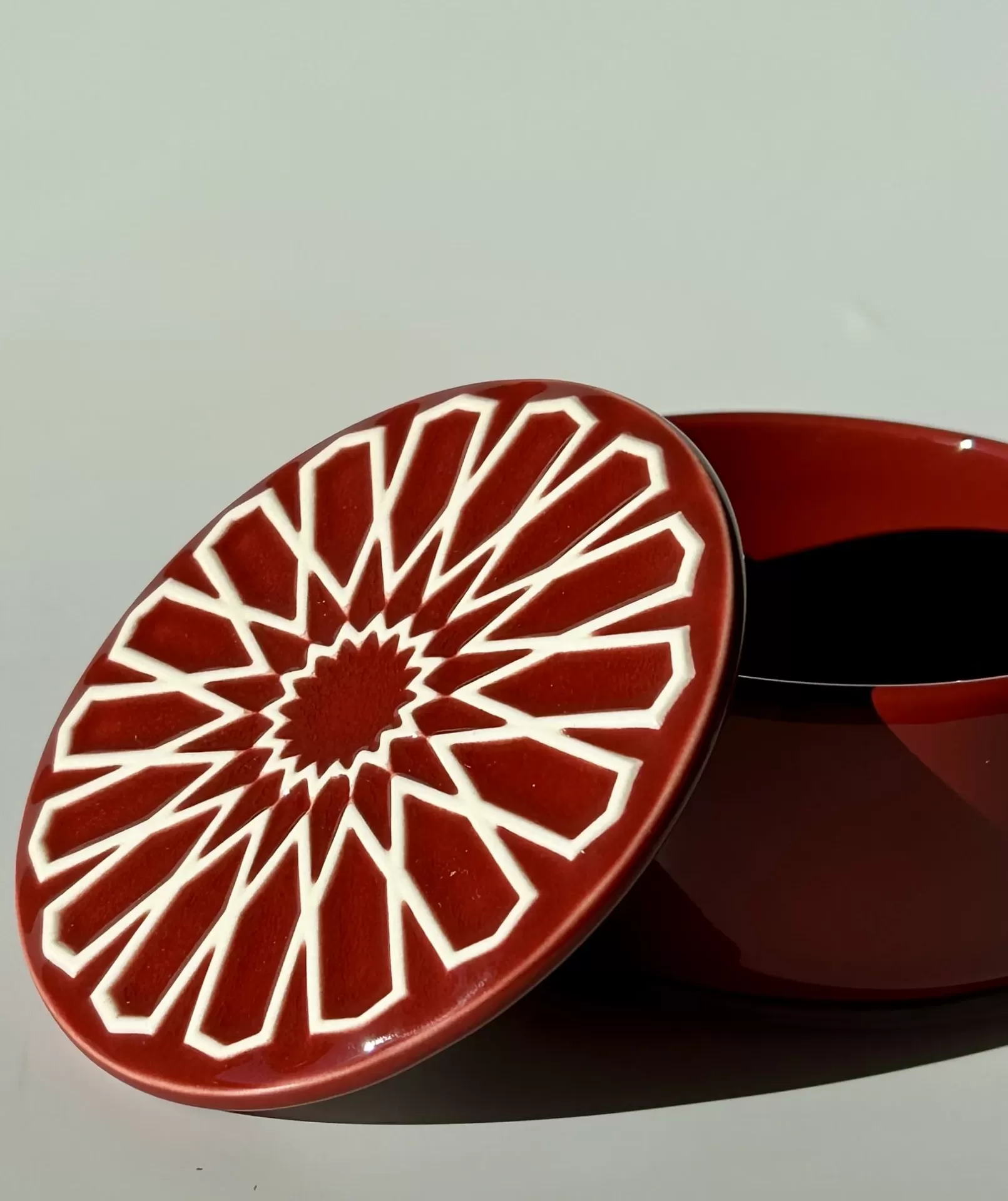 Frasco de cerâmica vermelha com tampa decorada com padrão geométrico branco