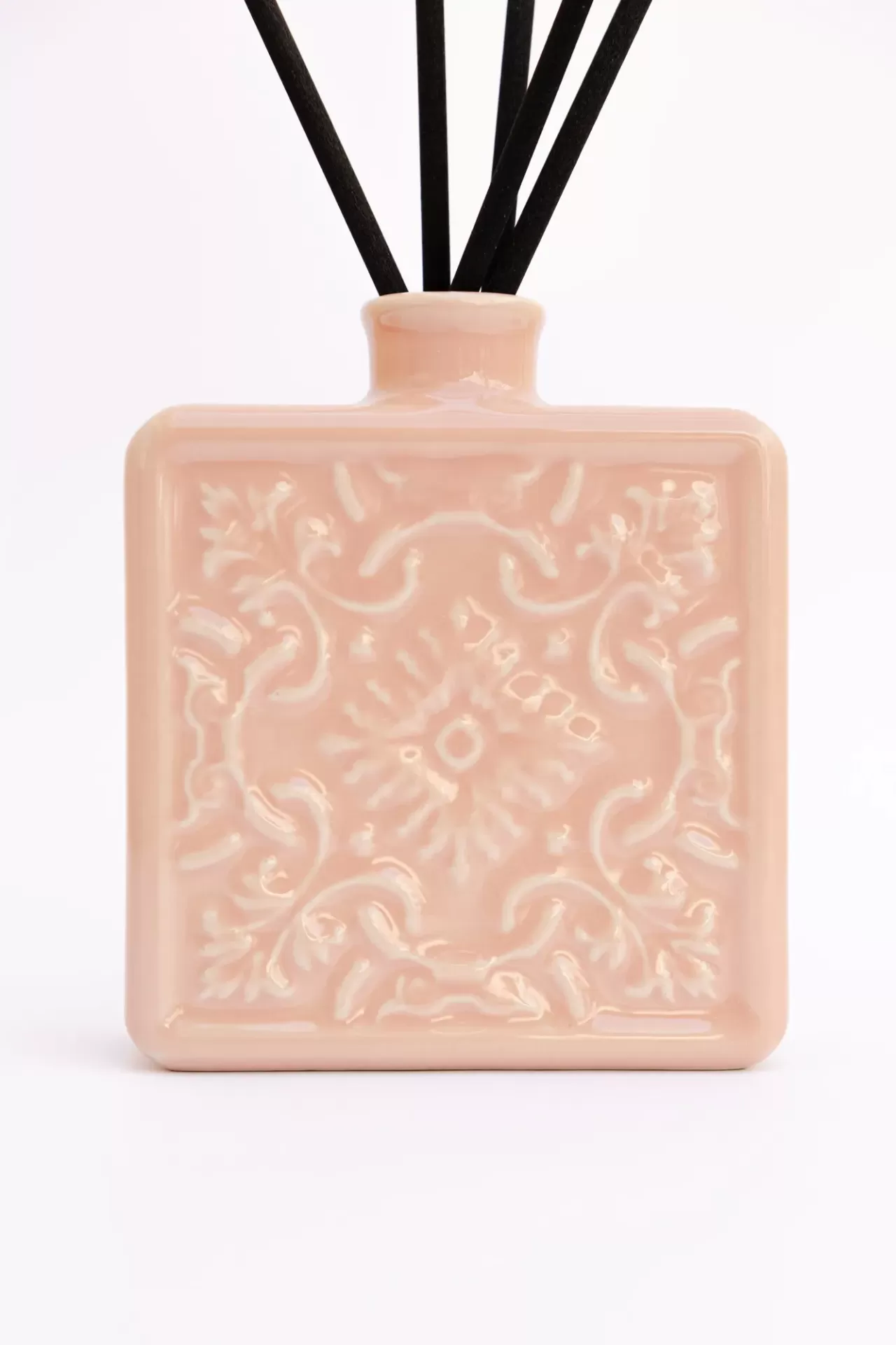 Frasco quadrado cor de rosa com padrão em relevo e varetas pretas para aromatizador