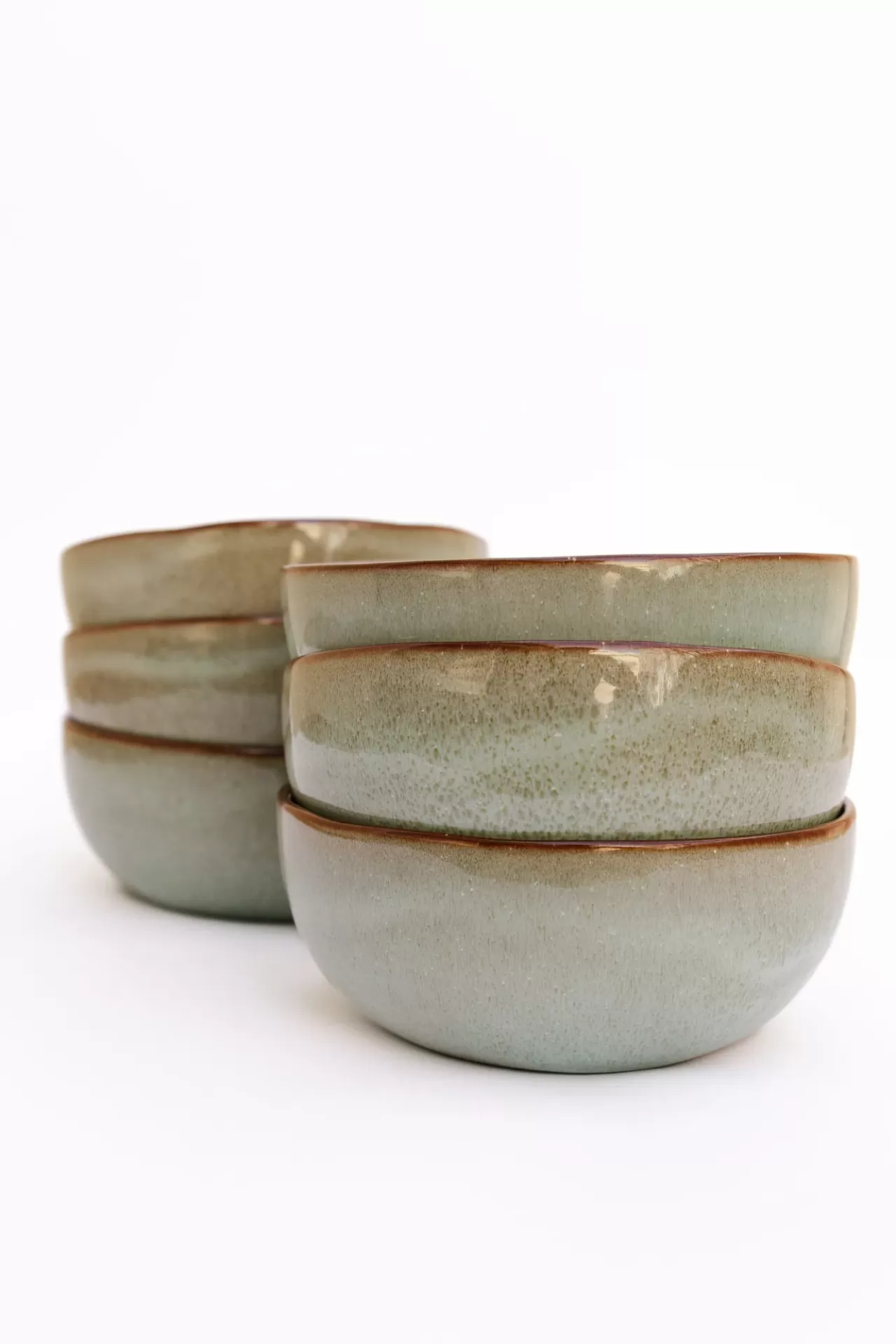 Conjunto de seis tigelas de cerâmica verde com bordas castanhas empilhadas