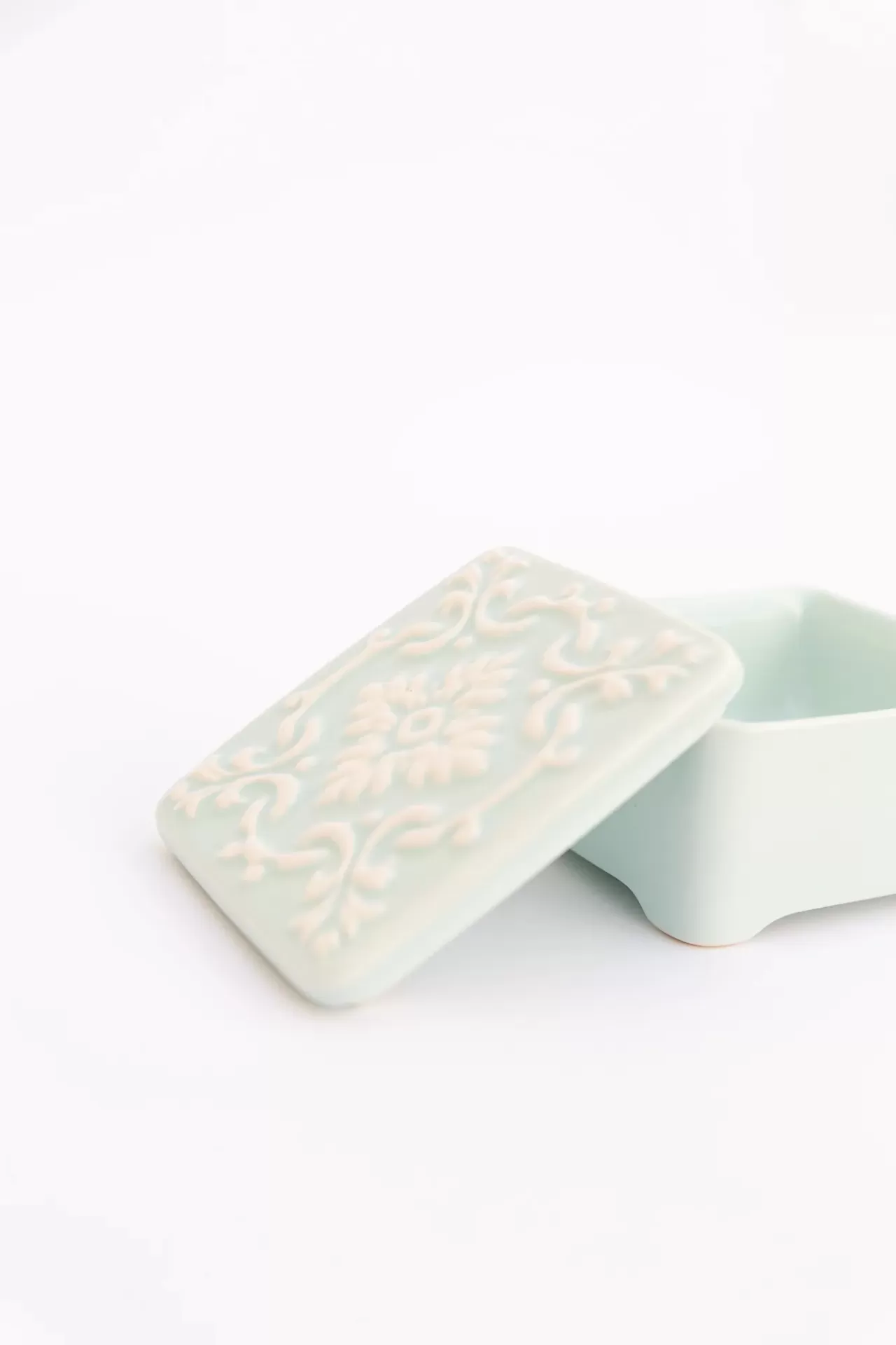 Caixa pequena azul claro em cerâmica com tampa decorada em relevo branco