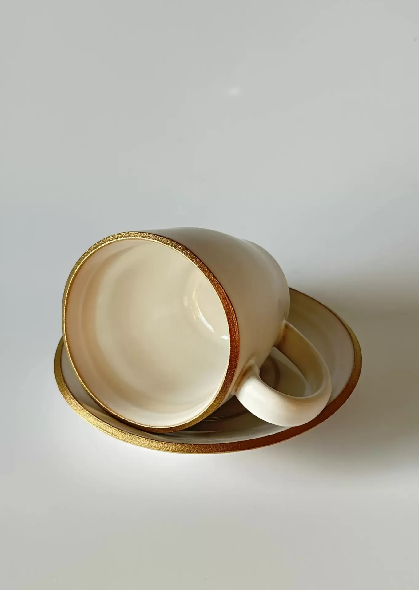 Conjunto de chávena e pires creme com borda dourada