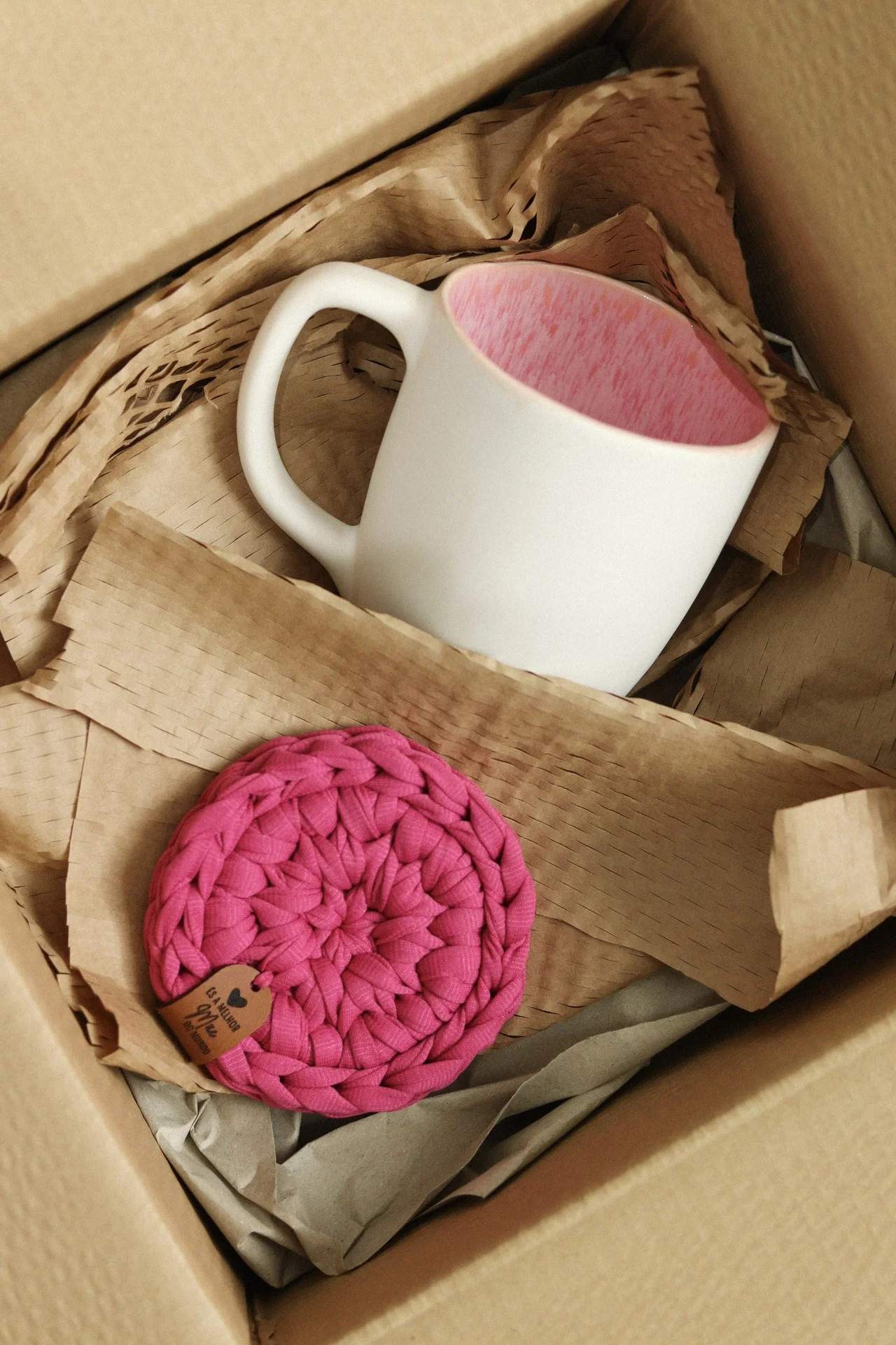 Caneca branca com interior rosa e suporte rosa dentro de caixa de cartão
