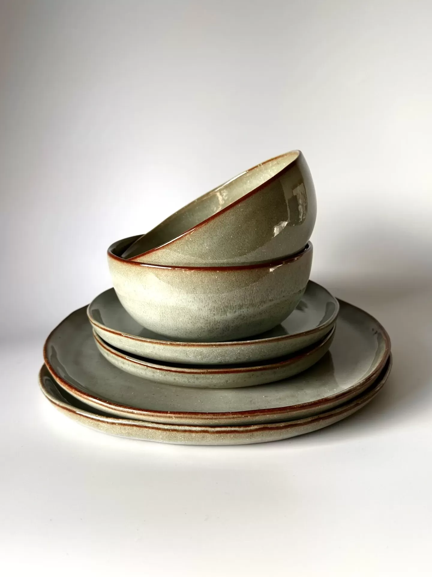 Conjunto de loiça em cerâmica cinzento esverdeado com bordas castanhas empilhado