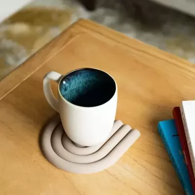 Caneca branca com interior azul em base bege numa mesa de madeira clara