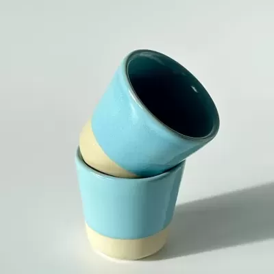 Dois copos de cerâmica azul turquesa empilhados sobre fundo branco