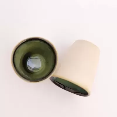 Copos de cerâmica com interior verde escuro e exterior branco sobre fundo branco