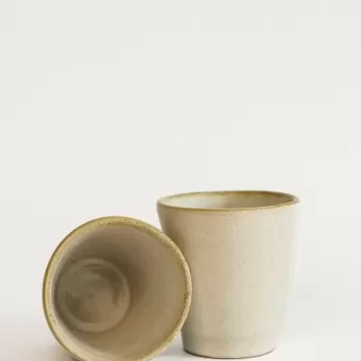 Duas peças de cerâmica creme, copos, sobre fundo branco.