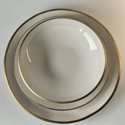 Conjunto de pratos brancos com bordas douradas empilhados visto de cima