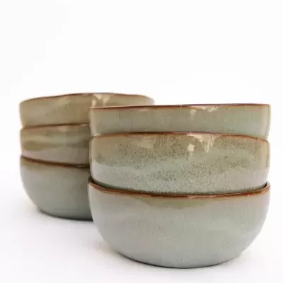 Conjunto de seis tigelas de cerâmica verde com bordas castanhas empilhadas