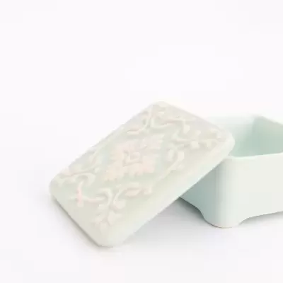 Caixa pequena azul claro em cerâmica com tampa decorada em relevo branco