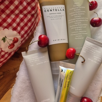 Produtos cosméticos e cremes em cestinho branco com tecido branco e cerejas
