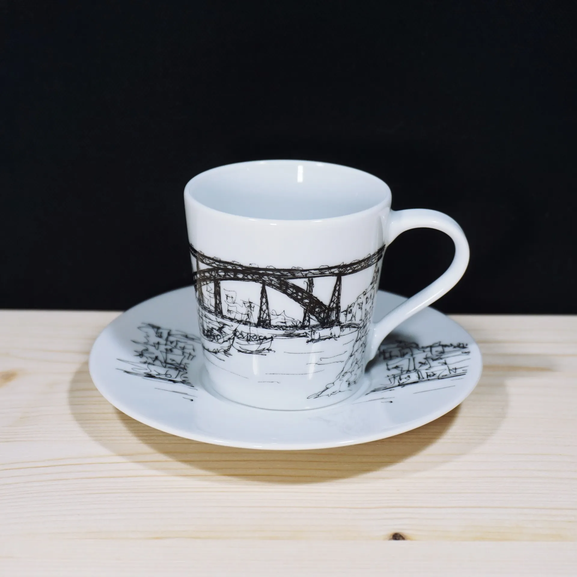 Cidades, Porto Collection, Ponte D. Luís I - Chávena de café Vista de trás de uma chávena de café de porcelana branca com pires, destacando a cidade do Porto