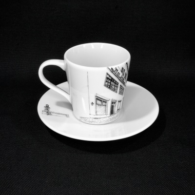 Chávena e pires em porcelana branca com desenho preto de edifícios.