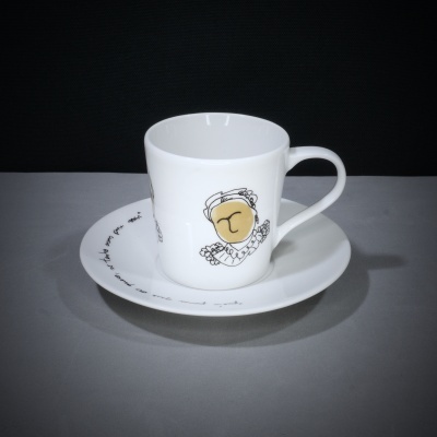 Chávena branca com botão dourado e pires branco com escrita