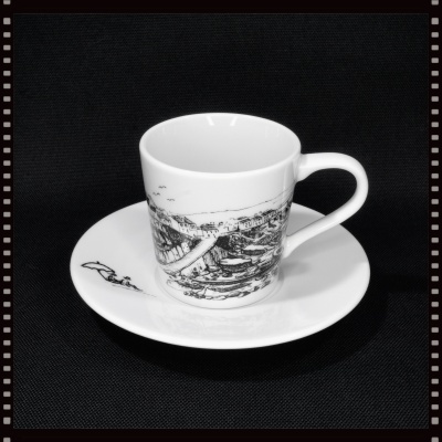 Conjunto de chávena e pires em porcelana branca com ilustrações a preto.