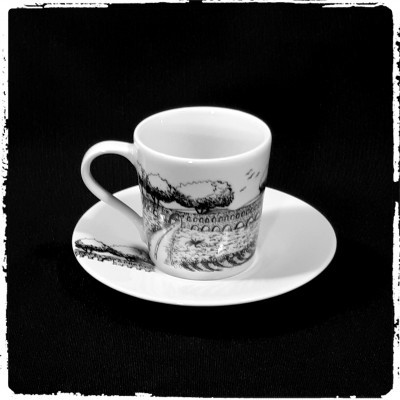 Chávena de café em porcelana branca com padrão preto e pires branco num fundo preto