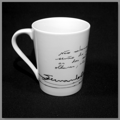 Caneca branca com texto manuscrito preto sobre fundo preto