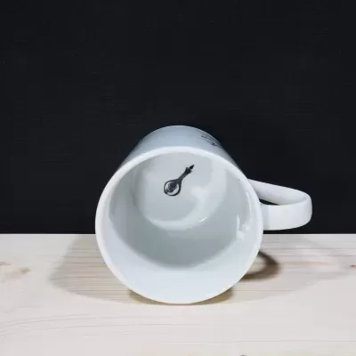 Vista do interior de uma caneca de porcelana branca, revelando uma pequena ilustração detalhada