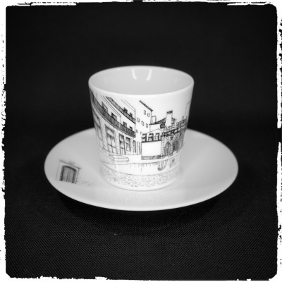 chávena e pires em porcelana branca com desenho de edifícios em preto