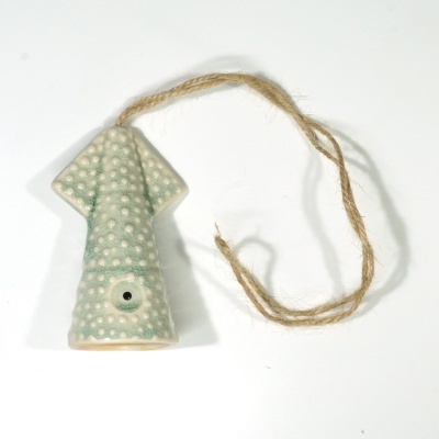 Produto cerâmico verde em forma de seta com fio de juta pendurado